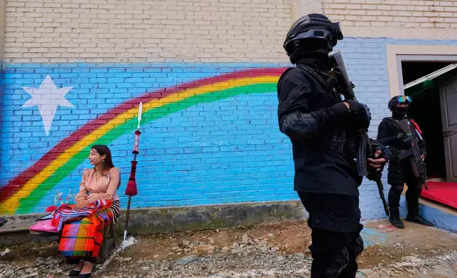 A woman sits in front of a graffiti of the Naga flag, near cadres of the National Socialist Council of Nagaland (Isak-Muivah) cadres in Ukhrul, in the northeastern Indian state of Manipur, Wednesday, Oct. 22, 2025. (AP Photo/Anupam Nath)