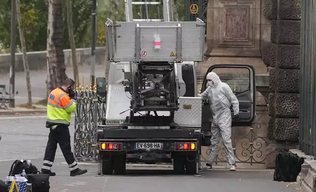 Police officers look for clues by a basket lift used by thieves Sunday, Oct. 19, 2025 at the Louvre museum in Paris. (AP Photo/Thibault Camus)