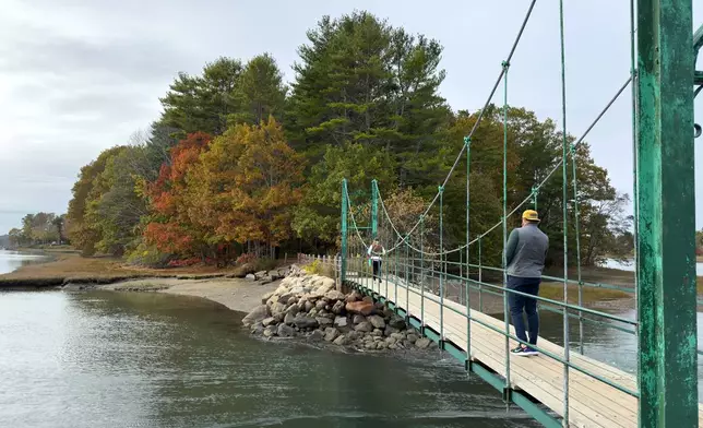 Visitors walk on Wiggly Bridge in York, Maine, on their way to view fall foliage on Tuesday, Oct. 14, 2025. (AP Photo/Rodrique Ngowi)
