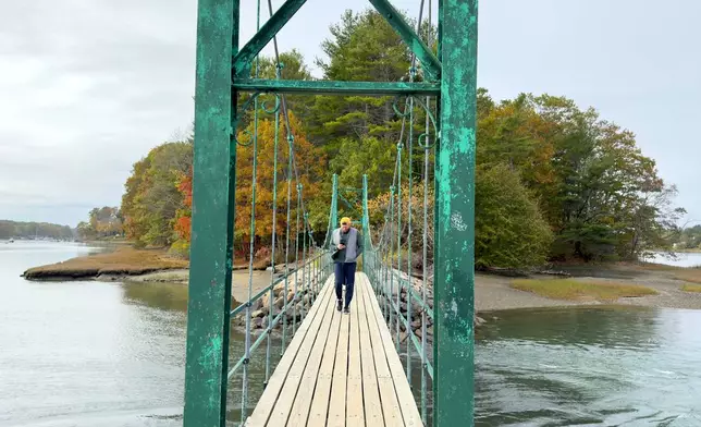 Visitors walk on Wiggly Bridge in York, Maine, on their way to view fall foliage on Tuesday, Oct. 14, 2025. (AP Photo/Rodrique Ngowi)