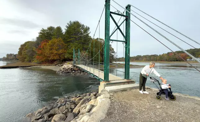 Visitors walk on Wiggly Bridge in York, Maine, on their way to view fall foliage on Tuesday, Oct. 14, 2025. (AP Photo/Rodrique Ngowi)