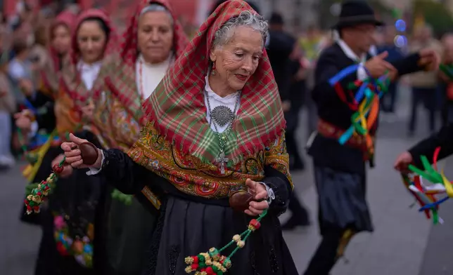 People in regional traditional costumes take part in the herding of sheep through central Madrid, Spain, as shepherds lead the animals through the streets in defense of ancient grazing and migration rights, Sunday, Oct. 19, 2025. (AP Photo/Manu Fernandez)