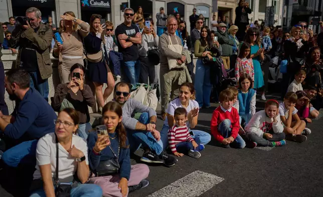 People watch as sheep are guided through central Madrid, Spain, moving through the streets in defense of ancient grazing and migration rights, Sunday, Oct. 19, 2025. (AP Photo/Manu Fernandez)
