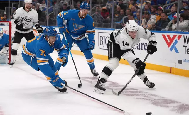Los Angeles Kings' Alex Laferriere (14) passes as St. Louis Blues' Mathieu Joseph (71) and Philip Broberg (6) defend during the first period of an NHL hockey game Tuesday, Oct. 21, 2025, in St. Louis. (AP Photo/Jeff Roberson)
