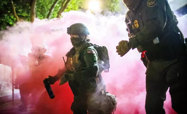 Police and federal officers throw gas canisters to disperse protesters near a U.S. Immigration and Customs Enforcement facility in Portland, Ore. on Sunday, Oct. 5, 2025. (AP Photo/Ethan Swope)
