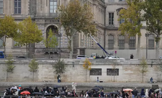 Police officers, background, look for clues by a basket lift used by thieves Sunday, Oct. 19, 2025 at the Louvre museum in Paris. (AP Photo/Thibault Camus)