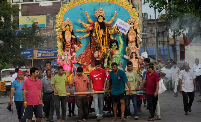 Devotees carry an idol of Hindu goddess Durga to immerse in river Brahmaputra in Guwahati, Thursday, Oct. 2, 2025. (AP Photo/Anupam Nath)