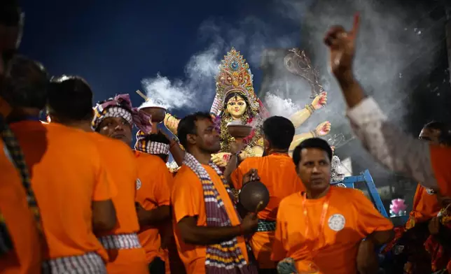 Devotees carry an idol of the Hindu goddess Durga for immersion in the Buriganga River marking the end of Durga Puja in Dhaka, Bangladesh, Thursday, Oct. 2, 2025. (AP Photo/Mahmud Hossain Opu)