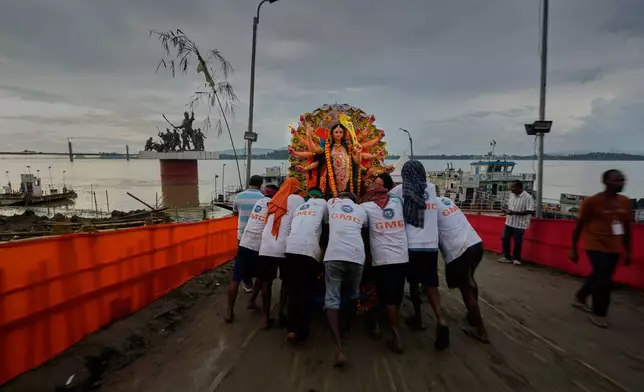 Municipal employees carry an idol of Hindu goddess Durga to emmers in river Brahmaputra in Guwahati, Thursday, Oct. 2, 2025. (AP Photo/Anupam Nath)