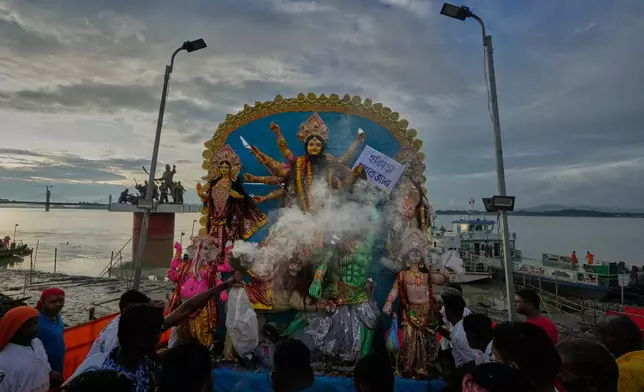Devotees carry an idol of Hindu goddess Durga to emmers in river Brahmaputra in Guwahati, Thursday, Oct. 2, 2025. (AP Photo/Anupam Nath)