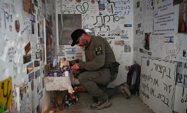 An Israeli soldier lights candles in a roadside bomb shelter where people were killed during the deadly Oct. 7, 2023, Hamas attack near the Israel-Gaza border, as Israel marks the second anniversary of the attack, Tuesday, Oct. 7, 2025. (AP Photo/Ohad Zwigenberg)