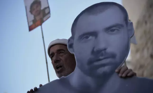 A man holds a poster with a portrait of an Israeli hostage held by Hamas in the Gaza Strip during a protest demanding the hostages' immediate release and calling for a ceasefire, in Jerusalem, Tuesday, Oct. 7, 2025, on the second anniversary of Hamas' cross-border attack on Israel on Oct. 7, 2023, which sparked the ongoing war in Gaza. (AP Photo/Leo Correa)