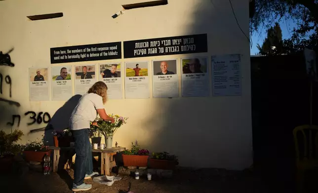 A woman places flowers during a memorial marking two years since the deadly Oct. 7, 2023, Hamas cross-border attack on Israel, in Kibbutz Kfar Aza, southern Israel where many of its community members were Killed and abducted, Tuesday, Oct. 7, 2025. (AP Photo/Ohad Zwigenberg)