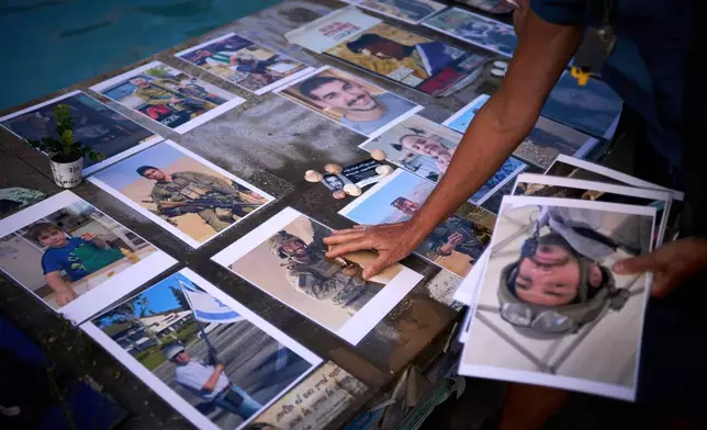 Activists place photos of Israelis who were killed in the Oct. 7, 2023 deadly Hamas attack on Israel, at a memorial marking two years anniversary of the assault, in Tel Aviv, Israel, Tuesday, Oct. 7, 2025. (AP Photo/Emilio Morenatti)