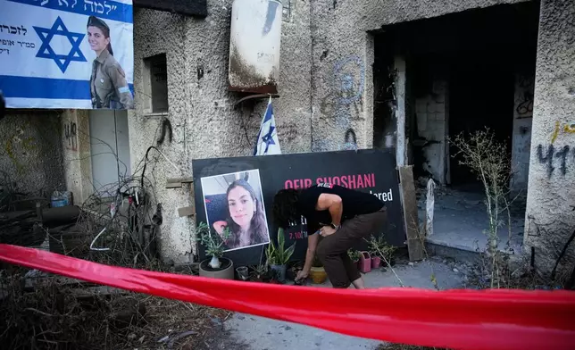 A woman places a candle at a tribute for Ofir Shoshani during a memorial marking two years since the deadly Hamas cross-border attack on Israel, in Kibbutz Kfar Aza, Tuesday, Oct. 7, 2025. (AP Photo/Ohad Zwigenberg)