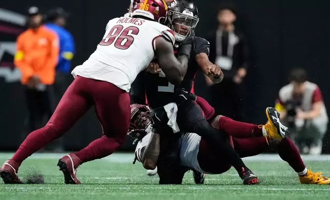 Atlanta Falcons quarterback Michael Penix Jr., right, is sacked by Washington Commanders linebacker Frankie Luvu, below, during the first half of an NFL football game, Sunday, Sept. 28, 2025, in Atlanta. (AP Photo/Brynn Anderson)