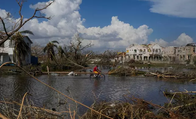A man rides his bicycle through an inundated street in Black River, Jamaica, Thursday, Oct. 30, 2025, in the aftermath of Hurricane Melissa. (AP Photo/Matias Delacroix)