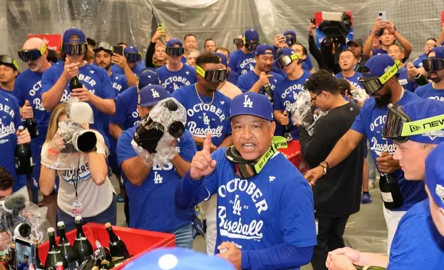 Los Angeles Dodgers manager Dave Roberts celebrates in the clubhouse with his team after a win over the Cincinnati Reds in Game 2 of the National League Wild Card baseball playoff series Wednesday, Oct. 1, 2025, in Los Angeles. (AP Photo/Mark J. Terrill)