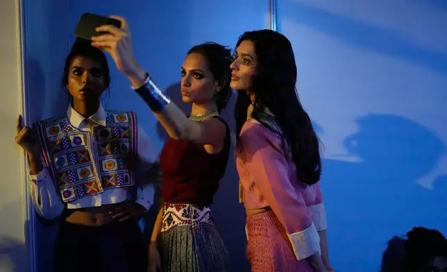 Models take selfies as they wait back stage to walk on the ramp presenting Indian designers creations during the Lakmé Fashion Week in partnership with Fashion Design Council of India or FDCI in New Delhi, India, Thursday, Oct. 9, 2025. (AP Photo/Manish Swarup)