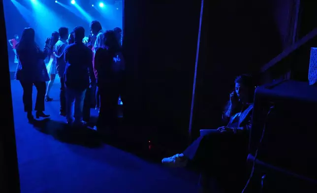 A stage coordinator talks on her mobile phone before the start of a show during the Lakmé Fashion Week in partnership with Fashion Design Council of India or FDCI in New Delhi, India, Thursday, Oct. 9, 2025. (AP Photo/Manish Swarup)