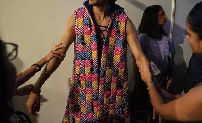 Make up artists applies a cream on the hands of a model back stage just before the start of a show during the Lakmé Fashion Week in partnership with Fashion Design Council of India or FDCI in New Delhi, India, Thursday, Oct. 9, 2025. (AP Photo/Manish Swarup)