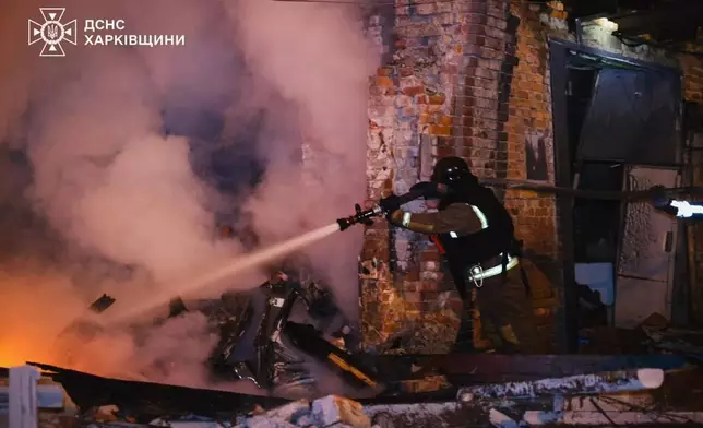 In this photo provided by the Ukrainian Emergency Services on Tuesday, Oct. 14, 2025, a rescue worker puts out a fire of a hospital damaged by a Russian strike in Kharkiv, Ukraine. (Ukrainian Emergency Service via AP)