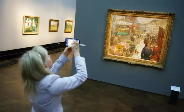 A visitor photographs the painting titled "Place Clichy" from 1867-1947 by Pierre Bonnard at a press preview for the exhibition "The Scharf Collection: Goya – Monet – Cezanne – Bonnard – Grosse" at the Alte Nationalgalerie museum in Berlin, Wednesday, Oct. 22, 2025. (AP Photo/Maryam Majd)