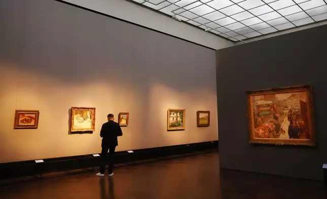 A visitor looks at a paintings with Pierre Bonnard's "Place Clichy" on the right, during a press preview of the exhibition "The Scharf Collection: Goya – Monet – Cezanne – Bonnard – Grosse" at the Alte Nationalgalerie museum in Berlin, Wednesday, Oct. 22, 2025. (AP Photo/Maryam Majd)