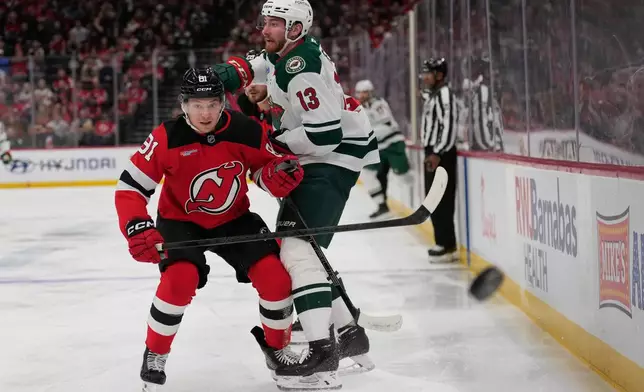 New Jersey Devils' Dawson Mercer, left, and Minnesota Wild's Yakov Trenin (13) look after the puck during the first period of an NHL hockey game Wednesday, Oct. 22, 2025, in Newark, N.J. (AP Photo/Seth Wenig)