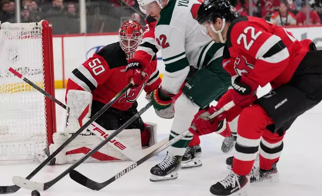 New Jersey Devils goaltender Nico Daws, left, defends the goal during the first period of an NHL hockey game against the Minnesota Wild Wednesday, Oct. 22, 2025, in Newark, N.J. (AP Photo/Seth Wenig)