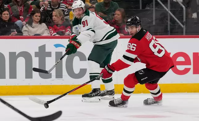 Minnesota Wild's Vladimir Tarasenko, left, passes past New Jersey Devils' Jack Hughes during the first period of an NHL hockey game Wednesday, Oct. 22, 2025, in Newark, N.J. (AP Photo/Seth Wenig)