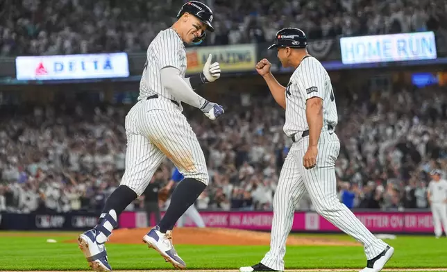New York Yankees' Aaron Judge celebrates with third base coach Luis Rojas after hitting a three-run home run against the Toronto Blue Jays during the fourth inning of Game 3 of baseball's American League Division Series, Tuesday, Oct. 7, 2025, in New York. (AP Photo/Yuki Iwamura)