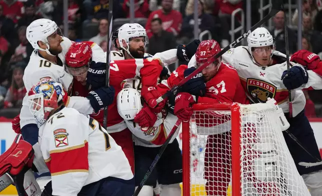 Detroit Red Wings and Florida Panthers players clutch and grab each other in the second period of an NHL hockey game Wednesday, Oct. 15, 2025, in Detroit. (AP Photo/Paul Sancya)