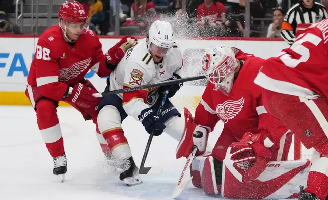 Detroit Red Wings goaltender Cam Talbot (39) stops a Florida Panthers right wing Mackie Samoskevich (11) shot as Patrick Kane (88) defends in the first period of an NHL hockey game Wednesday, Oct. 15, 2025, in Detroit. (AP Photo/Paul Sancya)