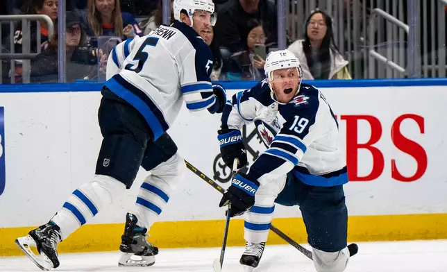 Winnipeg Jets center Jonathan Toews (19) passes the puck during the third period of an NHL hockey game against the New York Islanders, Monday, Oct. 13, 2025, in Elmont, N.Y. (AP Photo/Angelina Katsanis)