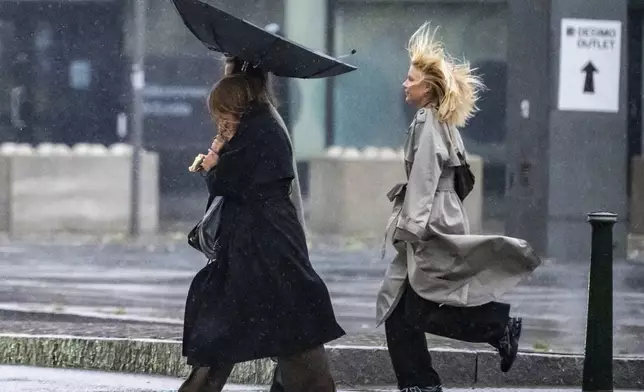 People struggle against the wind and rain in Malmö, Sweden, after a storm reached southern Sweden, Saturday Oct. 4, 2025. (Johan Nilsson/TT via AP)