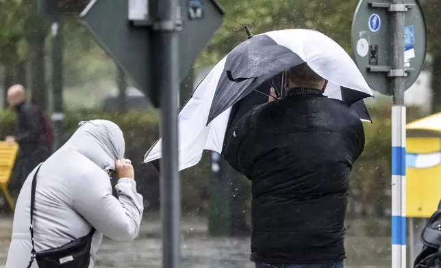 People struggle against the wind and rain in Malmö, Sweden, after a storm reached southern Sweden, Saturday Oct. 4, 2025. (Johan Nilsson/TT via AP)