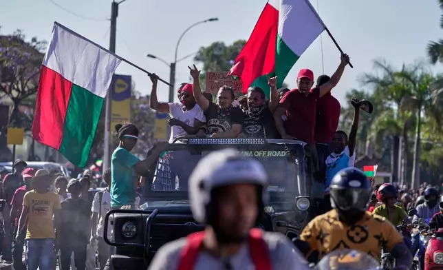 Protesters dance on top of a car during a protest calling for President Andry Rajoelina to step down in Antananarivo, Madagascar, Tuesday, Oct. 14, 2025. (AP Photo/Brian Inganga)