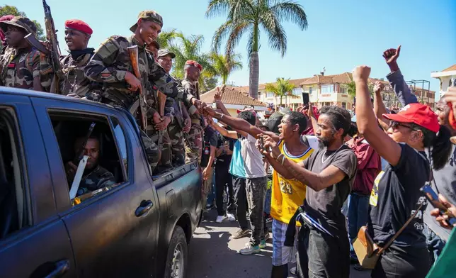 Soldiers are greeted by people gathering for a ceremony in tribute to demonstrators killed during recent anti-government protest in Antananarivo, Madagascar, Sunday, Oct. 12, 2025. (AP Photo/Mamyrael)