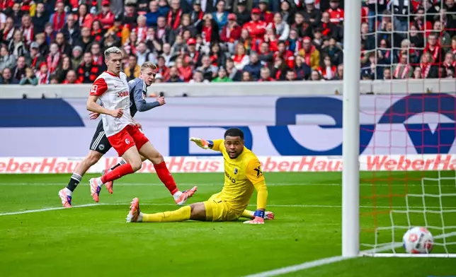 Eintracht Frankfurt's Jonathan Burkardt scores a goal past Freiburg's goalkeeper Noah Atubolu, during a German Bundesliga soccer match between SC Freiburg and Eintracht Frankfurt, in Freiburg im Breisgau, Germany, Sunday, Oct. 19, 2025. (Harry Langer/dpa via AP)