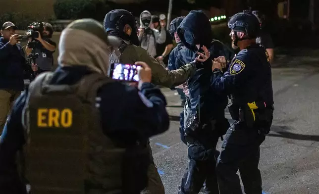 A protester is arrested by police and federal officers outside a U.S. Immigration and Customs Enforcement facility in Portland, Ore., Monday, Oct. 6, 2025. (AP Photo/Ethan Swope)