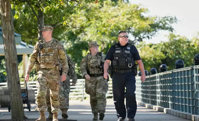 A Memphis Police Department officer, right, patrols with members of the National Guard, Friday, Oct. 10, 2025, in Memphis, Tenn. (AP Photo/George Walker IV)
