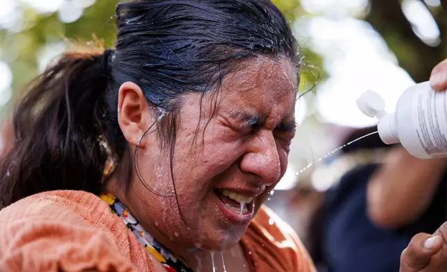 A protestor is doused with milk, water, and saline after tear gas in the Brighton Park neighborhood of Chicago, on Saturday, Oct. 4, 2025, after protesters learned that U.S. Border Patrol shot a woman Saturday morning on Chicago's Southwest Side. (Anthony Vazquez/Chicago Sun-Times via AP)