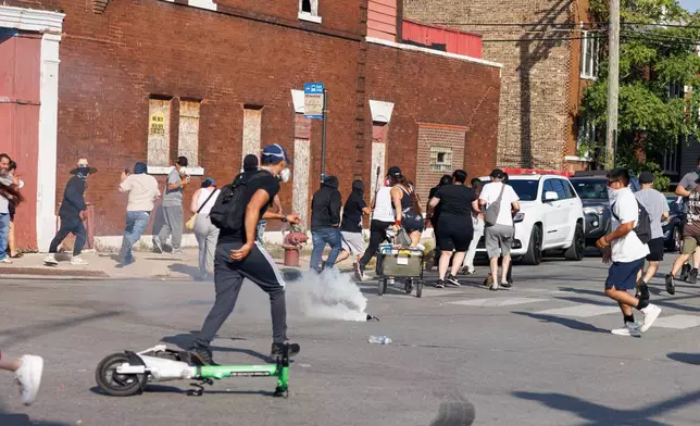 A gas canister erupts on the street in the Brighton Park neighborhood of Chicago, on Saturday, Oct. 4, 2025, after protesters learned that U.S. Border Patrol shot a woman Saturday morning on Chicago's Southwest Side. (Anthony Vazquez/Chicago Sun-Times via AP)