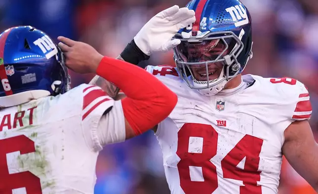 New York Giants tight end Theo Johnson (84) celebrates after catching a touchdown pass from quarterback Jaxson Dart, left, during the second half of an NFL football game against the Denver Broncos in Denver, Sunday, Oct. 19, 2025. (AP Photo/David Zalubowski)