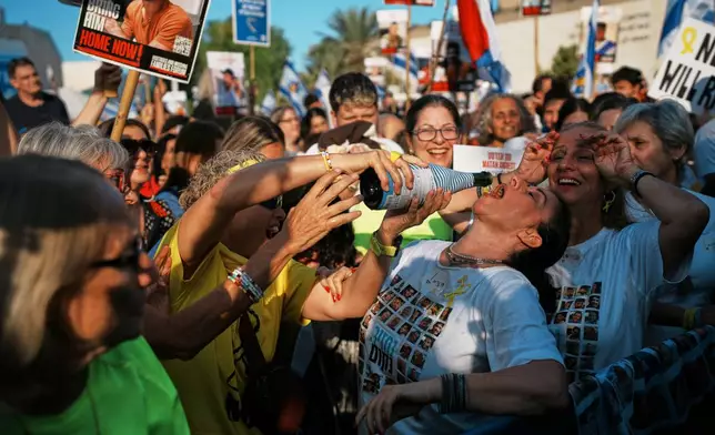 People react as they gather to watch a live broadcast of Israeli hostages released from Gaza at a plaza known as hostages square in Tel Aviv, Israel, Monday, Oct. 13, 2025. The release took place as part of a cease-fire agreement between Israel and Hamas. (AP Photo/Emilio Morenatti)