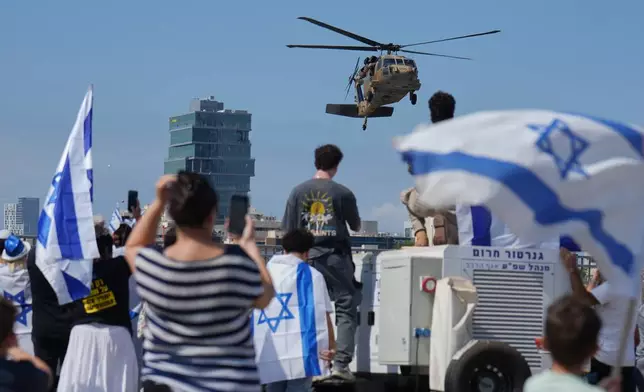 People wave Israeli flags as a military helicopter carrying Israeli freed hostages arrives at Beilinson hospital in Petah Tikva, Israel, after they were released from Hamas captivity in the Gaza Strip, Monday, Oct. 13, 2025. (AP Photo/Ariel Schalit)