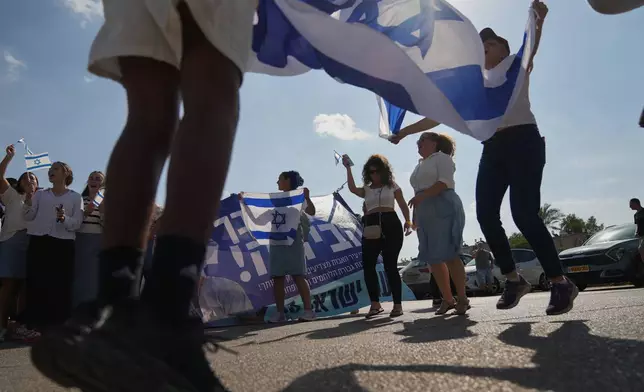 People wave Israeli flags in celebration as they wait outside Beilinson Hospital in Petah Tikva, Israel, where some of the freed hostages are expected to arrive after being released from Hamas captivity in the Gaza Strip, Monday, Oct. 13, 2025. (AP Photo/Francisco Seco)