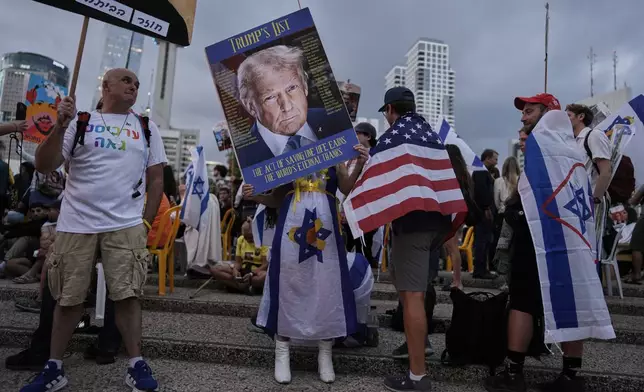 A woman holds an image of U.S. President Donald Trump during a gathering at a plaza known as hostages square in Tel Aviv, Israel, Monday, Oct. 13, 2025, before the release of Israeli hostages held in Gaza. (AP Photo/Oded Balilty)