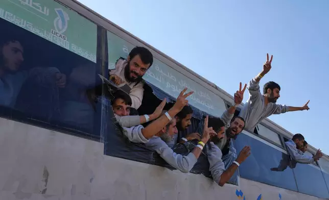 Freed Palestinian prisoners wave from a bus as they arrive in the Gaza Strip after their release from Israeli jails under a ceasefire agreement between Hamas and Israel, in Khan Younis, southern Gaza Strip, Monday, Oct. 13, 2025. (AP Photo/Jehad Alshrafi)